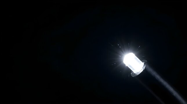 Single bright white LED light glowing against a dark black background