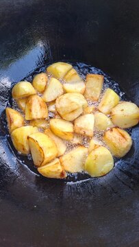 Potatoes, meat, and onions cut into large chunks in a cauldron.