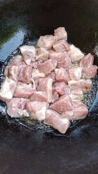 Potatoes, meat, and onions cut into large chunks in a cauldron.
