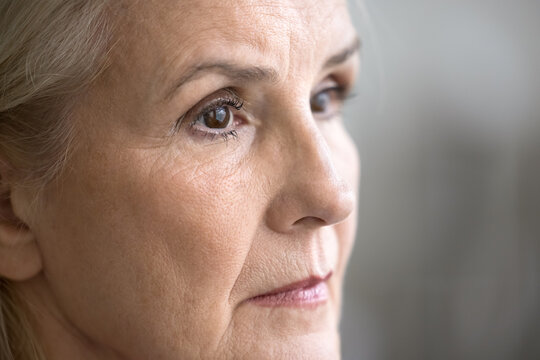 Cropped shot face sad unhappy elderly woman looking aside lost in difficult thoughts. One eye is blurred. Age related eyesight health problem cataract myopia bad vision or menopause concept. Close up