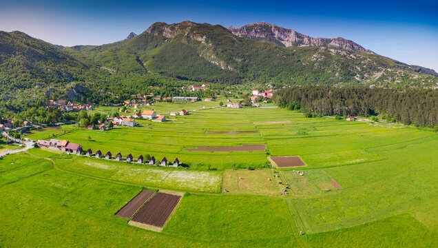 Njegusi village nestled in a mountain valley, showing traditional homes and green fields within Lovcen National Park, Montenegro