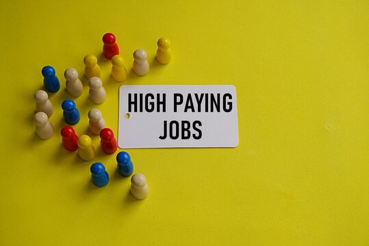 Wooden figure representing worker with HIGH PAYING JOBS printed card. Employment concept. High paying job search. Good salary offer from employer.