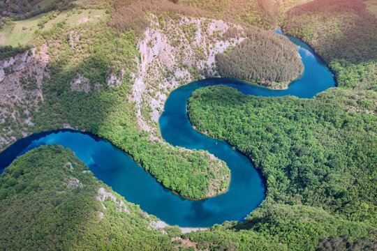 Aerial view of turquoise serpentine river winding through lush forested canyon. Nature concept.