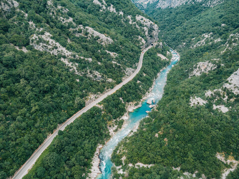 Moraca River Canyon showcasing green forested mountains, winding road, and vibrant turquoise river creating a dramatic landscape