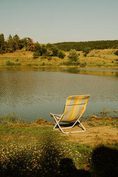 A stationary beach chair by the lakeside, featuring a relaxed atmosphere with yellow and gray upholstery.