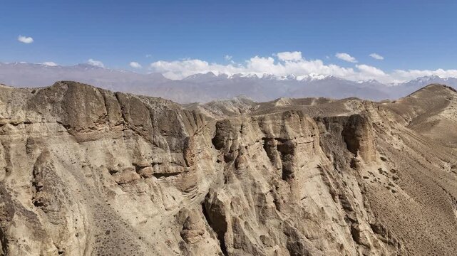 Forward drone flight approaching a small eroded hill on the rugged hillside of Dhakmar, Upper Mustang, Nepal. Dramatic aerial view of eroded terrain for travel and documentary projects.