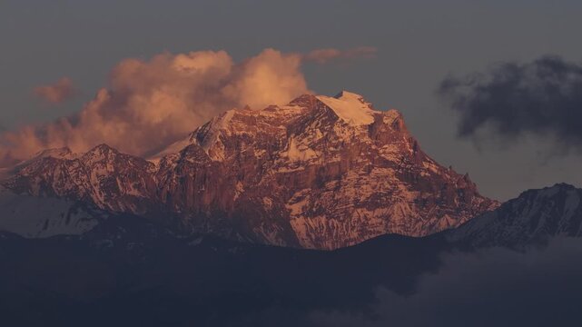 Telephoto drone shot moving right during golden hour as clouds drift across a mountain in Upper Mustang, Nepal. Cinematic Himalayan landscape ideal for travel and documentary projects.