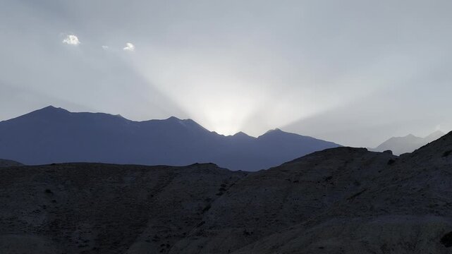 Aerial Drone shot of silhouettes of mountains during sunset as the drone passes a hill. Cinematic landscape captured in Nepal, ideal for travel, adventure, tourism, nature, and documentary projects.