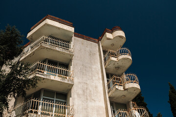 Weathered apartment building featuring multiple balconies under a clear blue sky. Residential...