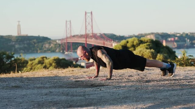 Athletic tattooed man doing push-ups outdoor workout