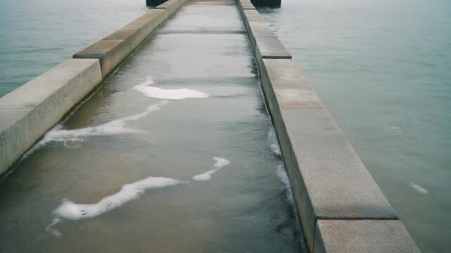 Clean concrete pier walkway partially submerged by calm seawater for municipal climate adaptation plans and government infrastructure reports.