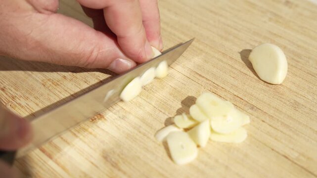 Slicing a Peeled Garlic Clove on Board