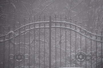 Fototapeta premium snowy gate to the jewish cemetery, cloudy snowy moody weather