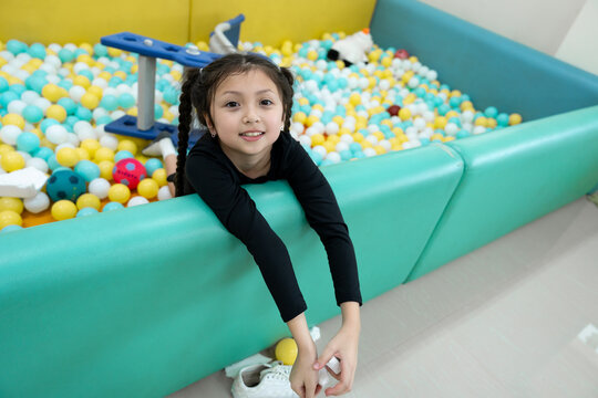 Smiling girl playing in ball pit tunnel