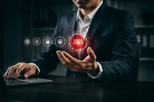 Businessman points to a red ddos attack alert on a digital interface while working on his laptop.