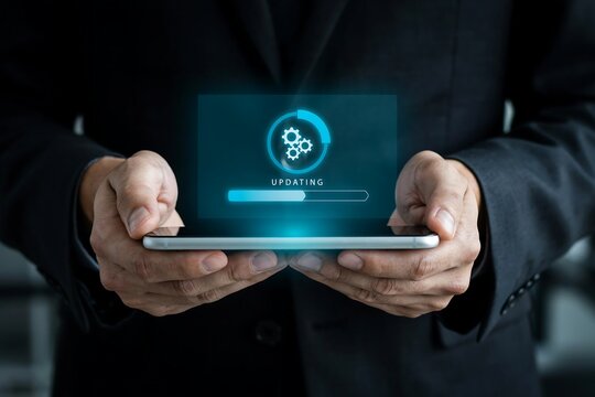Person holds a smartphone displaying an 'updating' progress bar with gears, signifying system updates and software installation.