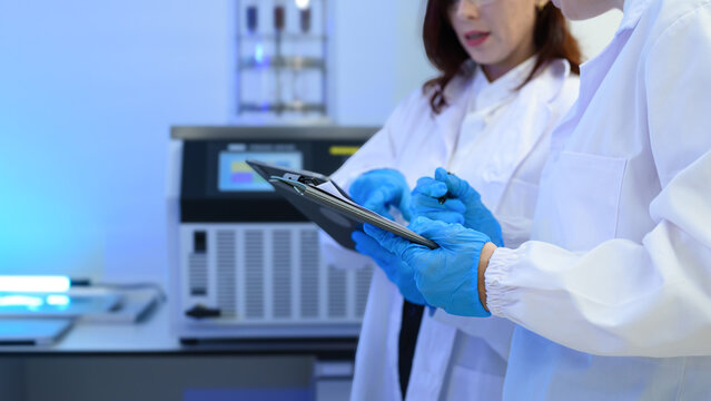 Female Scientist in White Lab Coat Writing on Clipboard in Modern Laboratory