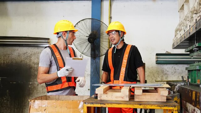 Two construction professionals working together on a project in a warehouse setting while wearing safety equipment