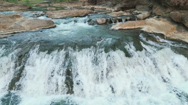 Beautiful slow motion view of rushing river stream and small waterfall with a dolly forward motion.