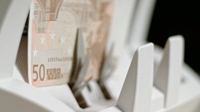 Fifty euro bills passing through the automatic currency counting machine in slow motion for financial cash processing in 4K Ultra HD footage
