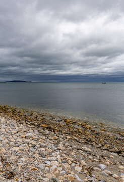 A grey moody seascape image, with a lone fishing boat on the horizon. Howth, Ireland.