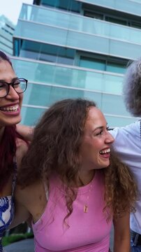 Vertical. Five cheerful multi-ethnic students are lifting their friend, laughing and having fun together in a park, enjoying their free time and friendship