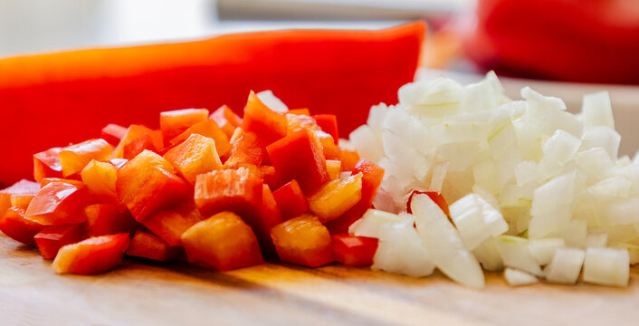 Chopped Red Bell Pepper and Diced White Onion on Wooden Cutting Board Close Up