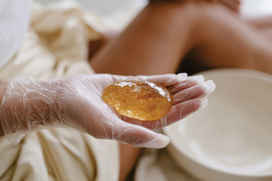An image of a gloved hand holding delicious-looking sugaring wax, representing the eco-friendly and organic approach to personal grooming and hair removal methods.