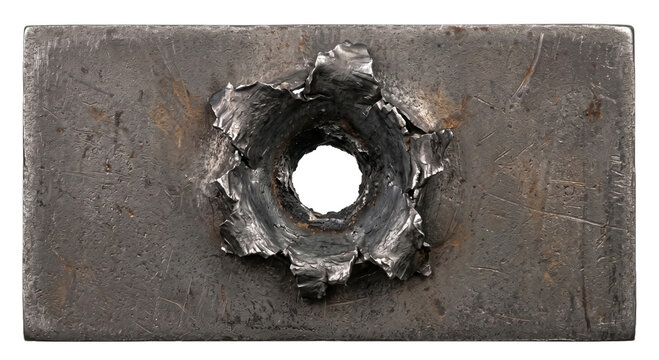 Close-up of a bullet hole with jagged metal edges on a textured steel plate