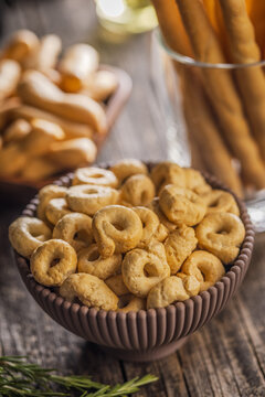 Rustic Italian Taralli Snack Bowl With Breadsticks Olive Oil and Fresh Rosemary on Wooden Table