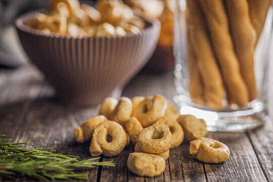 Rustic Italian Taralli Snacks and Grissini Breadsticks on Wooden Table with Fresh Rosemary