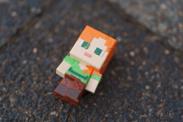 Fototapeta premium Dusseldorf, Germany - July 23 2026: Minecraft Alex figurine resting on pavement outdoors