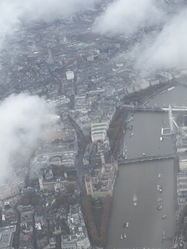 Aerial view of London city with the observation wheel, Elizabeth Tower, historic abbey, and Thames River from a plane.