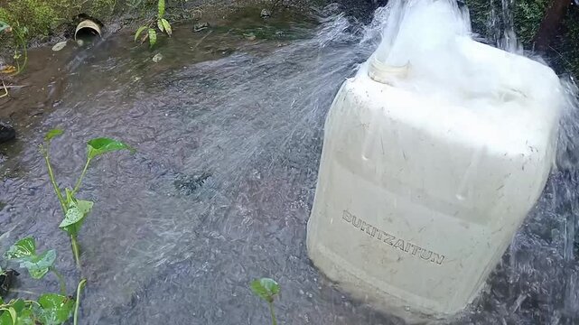 Splashing fresh spring water filling up a plastic jerrican at a rural natural fountain.