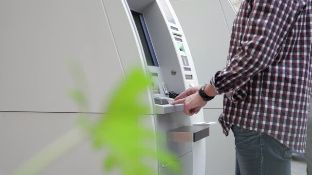 Man using ATM machine with close up handheld shot of person navigating screen and inserting card for banking transaction in 4K Ultra HD footage
