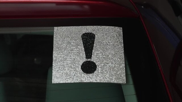 Exclamation mark warning sign made of rhinestones on car window.