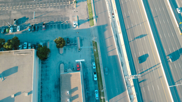 Direct overhead view captures multi lane expressway lanes running parallel to commercial parking lots in Northwest San Antonio. Frontage routes alongside Loop 410 border office spaces