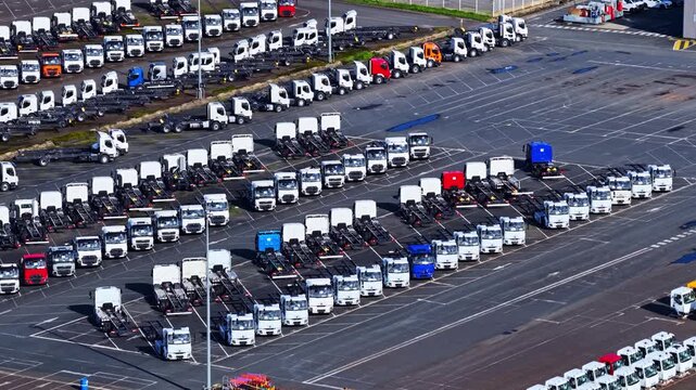 Aerial view of rows of trucks in a logistics parking lot, showing many commercial vehicles parked in an orderly fashion at a large distribution center, Europe.