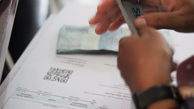 Businessman counts money in hands with selective focus on indonesian rupiah paper banknotes for corporate financial wealth management in 4K Ultra HD footage
