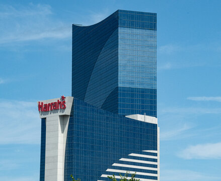 Harrah's casino and hotel tower in Atlantic City with reflective blue glass facade rising above the city, conveying modern architecture, urban luxury, tourism and corporate presence under a clear sky