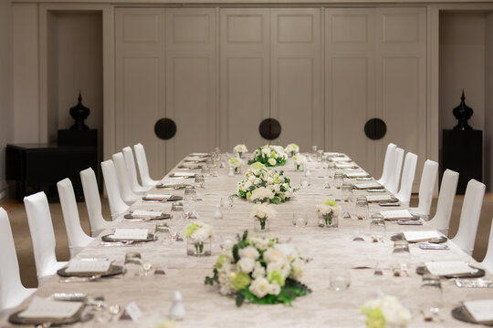 Elegant Executive Dining Table Setup with Floral Centerpieces in Luxury Boardroom