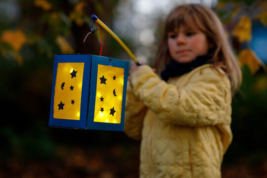 Closeup of little preschool kid girl holding selfmade traditional lanterns with candle for St. Martin procession. child happy about family parade in kindergarten. German tradition Martinsumzug