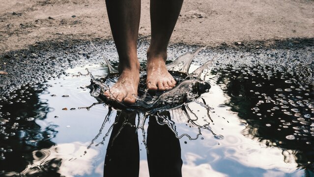 Bare feet stepping into a puddle with a splash