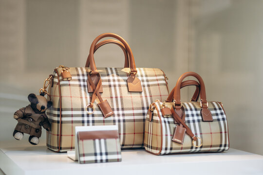 Nice, France - July 27, 2026: Burberry check handbags, cardholder and teddy bear charm displayed in a Galeries Lafayette window