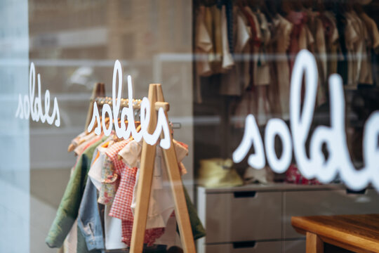 Children&rsquo;s clothing store window with garments behind the repeated French word &ldquo;Soldes&rdquo; (&ldquo;Sales&rdquo;)