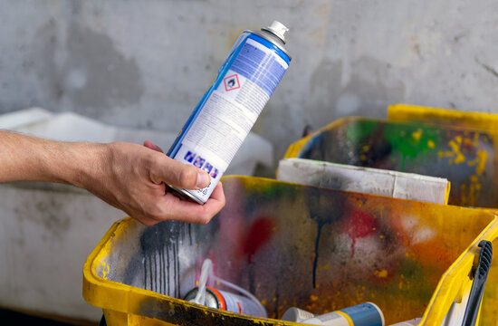 Disposing of chemical and flammable household waste at a community drop-off recycling station. Responsible citizen dropping an aerosol spray can with flammable hazard sign into a hazardous waste bin