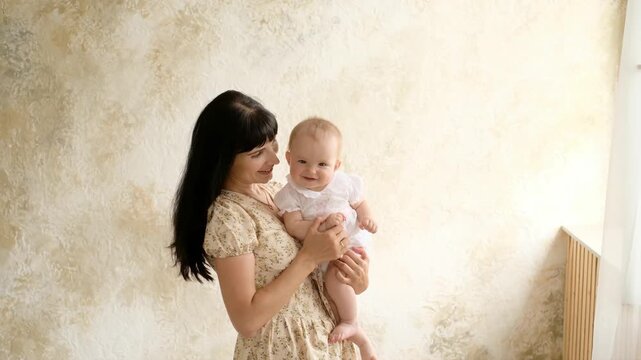 Mother and baby, a mother with her baby at home, maternal love and care, a mother gently hugs and kisses her little child, space for text.