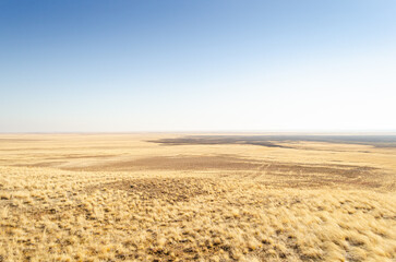 Fototapeta premium serene desert landscape with expansive dry grass and distant horizon viewed from a high angle in open desert setting with brown and blue tones and natural light.