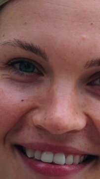 Vertical Portrait of Caucasian woman looking at camera and smiling outdoors. Beautiful eastern European girl is happy and cute. Positive and attractive and confident laughing standing outside