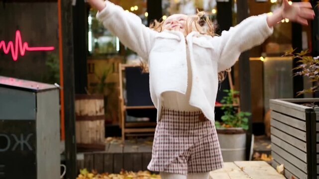 baby girl with yellow autumn leaves rejoices in autumn, making leaf fall and laughing, autumn walk